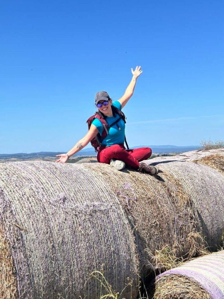 camminatrice travel designer su una balal di fieno in val d'orcia, toscana, vicino siena
